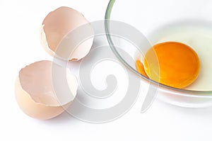 eggshell and Raw egg yolk in glass closeup isolated on white background