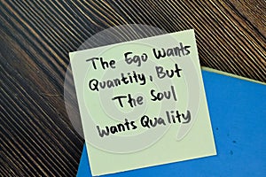 The ego wants quantity, but the soul wants quality write on sticky notes isolated on Wooden Table. Motivation concept
