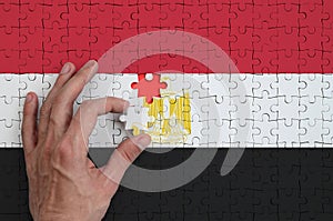 Egypt flag is depicted on a puzzle, which the man`s hand completes to fold