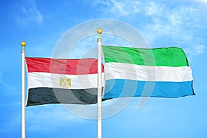 Egypt and Sierra Leone two flags on flagpoles and blue cloudy sky