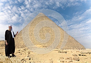 An Egyptian with a turban points a finger at the historic pyramid of Giza.