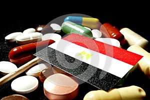 Egyptian flag with lot of medical pills isolated on black background