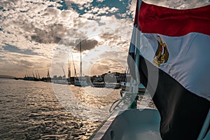 Egyptian flag waving in the wind on the front of a motor boat crusing down the river nile. Amazing view of the sunset accross the
