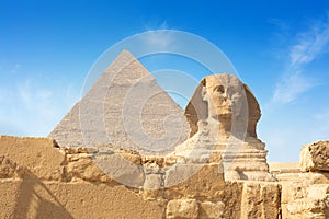 Egyptian Great Sphinx full body portrait with head, feet with all pyramids of Menkaure, Khafre, Khufu in background on a
