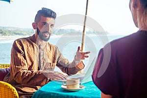 Egyptian man foreign language teacher teaching female student at tropical cafe