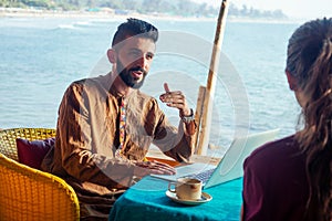 Egyptian man foreign language teacher teaching female student at tropical cafe