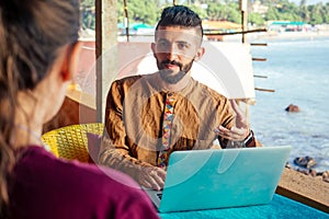 Egyptian man foreign language teacher teaching female student at tropical cafe