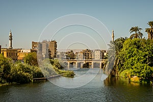 Egyptian town in the sunset with two minaretes and a bridge. A view from a cruise on the river Nile, Egypt. October 27, 2018 photo