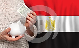 Egyptian woman with money bank on the background of Egypt flag. Dotations, pension fund, poverty, wealth, retirement concept