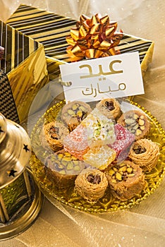 Eid gifts and sweets along with Ramadan lamp and message tag.