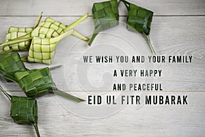 Eid Mubarak quote - We wish you and your family a very happy and peaceful Eid Ul Fitr Mubarak. With frame background of Ketupat.