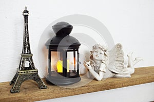 Eiffel statue, black lantern and fairy statue on wooden shelves