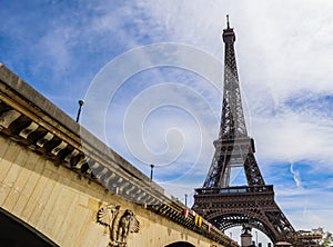 Eiffel Tower against blue sky with clouds and a bridge over Seine River. Paris France. April 2019