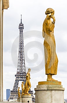 Eiffel Tower on the background of series of bronze sculptures on pedestals