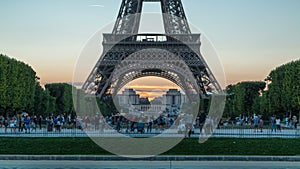 Eiffel Tower day to night timelapse and people sitting on the grass in the evening in Paris, France