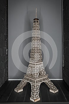 Eiffel Tower figurine made of simple material stands on a gray background of the room