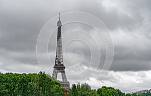 The Eiffel Tower over the trees with stormy clouds