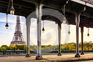 The Eiffel tower in Paris, France, with the pillars and street lights of the Bir-Hakeim bridge in the foreground by a sunny