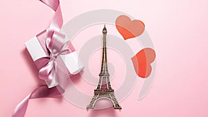 The Eiffel Tower, red hearts and white gift with purple ribbon bow on bright background. Stop motion animation with copy space.