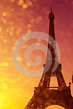 Eiffel Tower silhouette at sunset in Paris France with shiny golden bokeh lights