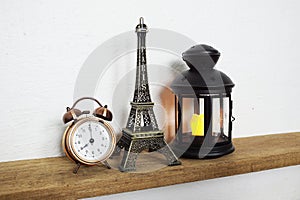 Eiffel tower statue, alarm clock and black lantern Home decoration accessories on wooden shelves