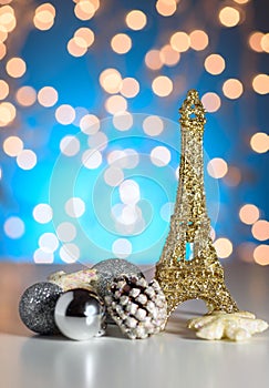 Eiffel Tower toy with Christmas / New Year decorations, ornaments. Blue golden bokeh background.