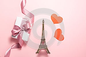 The Eiffel Tower, two red hearts and white gift box with purple ribbon bow on bright pink