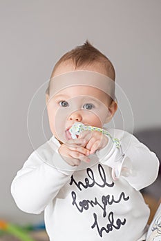 Eight months old baby girl bringing her pacifier to her mouth