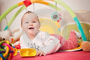 Eight months old baby girl playing with colorful toys