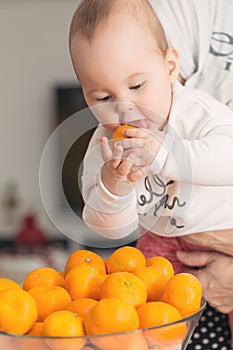 Eight months old baby girl sucking a tangerine