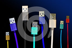 Eight multicolored usb cables are located vertically, on a dark, gloomy isolated background. The family unites. future technologie