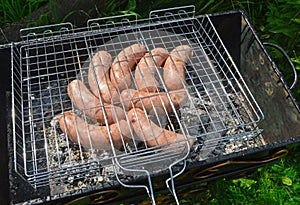 Eight sausages are fried on coals