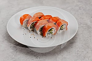 Eight servings of sushi with salmon and cucumber on a white plate.