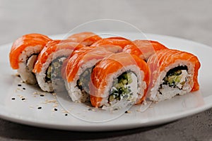 Eight servings of sushi with salmon and cucumber on a white plate.