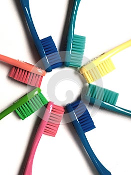 Eight toothbrushes of various colors arranged in a star shape on a white background.