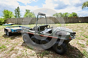 Eight-wheeled all-terrain vehicle with a trailer on a meadow on a summer day