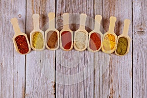 Eight wooden spoons of asian spices on wooden table