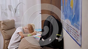 An eight-year-old boy is sitting reading a book at home at his desk.