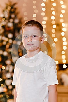 An eight-year-old boy in a white T-shirt looks at the camera