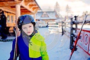 Eight years old boy in helmet on ski slope.