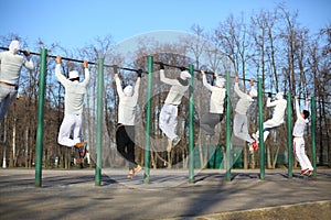 Eight young men training on the horizontal bar on photo