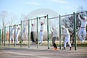 Eight young people hang on the horizontal bar on photo