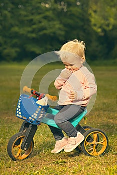 Eighteen months old baby girl on tricycle bike with albino ferret