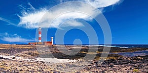 El Cotillo - Faro del Toston: Beautiful wild rugged coastal landscape, isolated red and white striped lighthouse,  clear blue sky