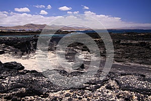 El Cotillo - Faro del Toston: View over black volcanic rocks and lagoon on village from beach La Concha north Fuerteventura