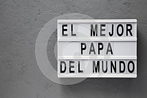 `El Mejor Papa Del Mundo` words on lightbox over gray surface. Overhead, from above, flat lay. Father`s day. Copy space photo