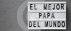 `El Mejor Papa Del Mundo` words on a modern board over gray surface. Overhead, from above, flat lay. Father`s day. Copy space photo
