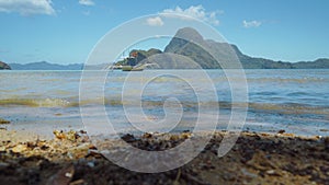 El Nido bay. Palawan, Philippines. Banca boat in lagoon. Calm waves rolling on sandy beach coastline. Cadlao island in