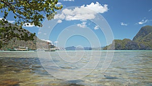 El Nido bay. Palawan, Philippines. Low angle view of Bangka boats floating in shallow bay by noon