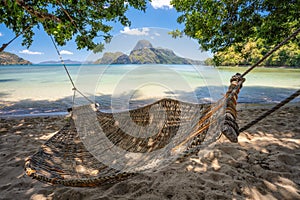 El Nido, Palawan, Philippines. A bamboo hammock in the shade with beautiful tropical cadlao island in morning light the